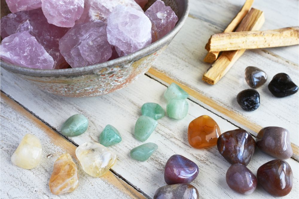 A top view image of rose quartz and various energy healing crystals on a white wooden table