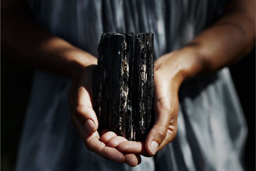 Woman's hands holding dark, powerful black tourmaline crystal