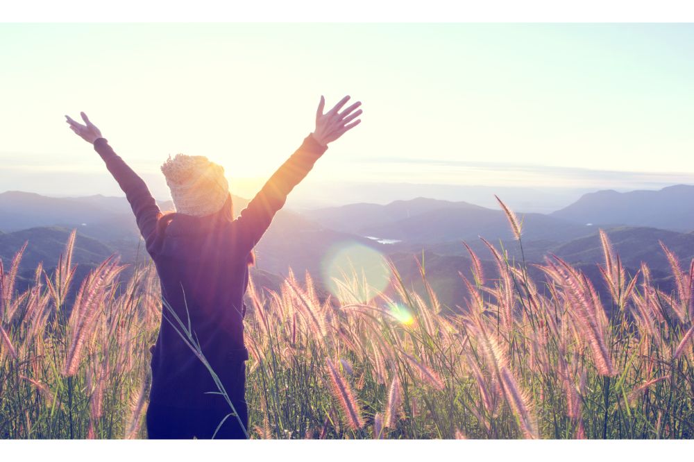 Happy Woman Enjoying Nature on grass meadow on top of mountain 