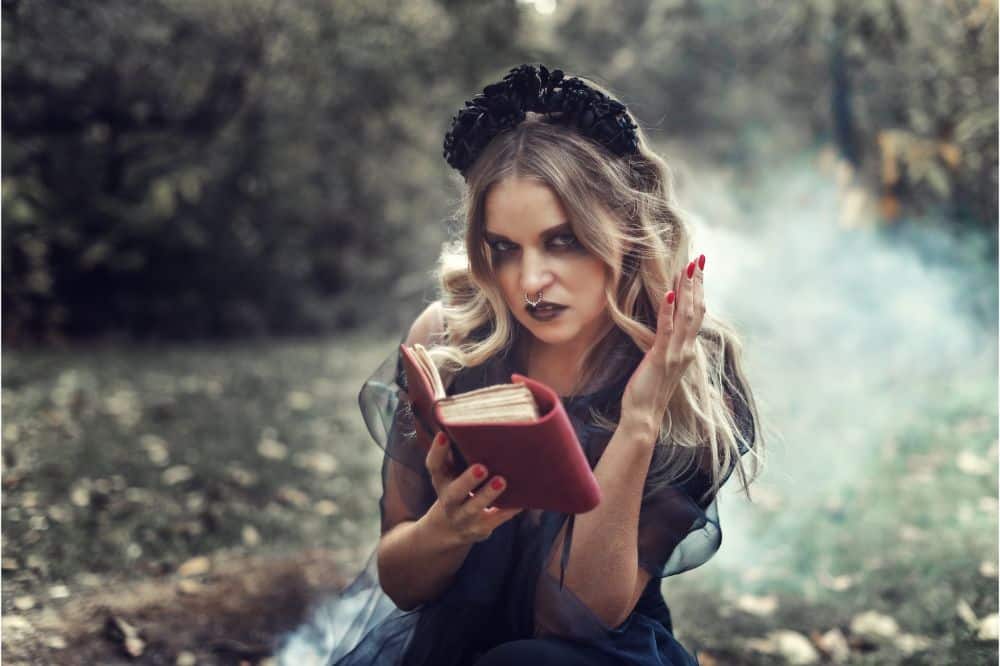 La bruja lanza un hechizo frente a un incendio en un bosque misterioso