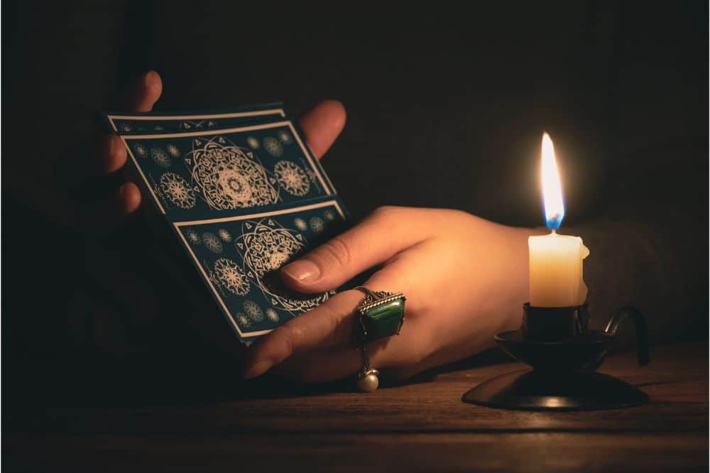 Fortune teller reading a future by tarot cards in the light of candle